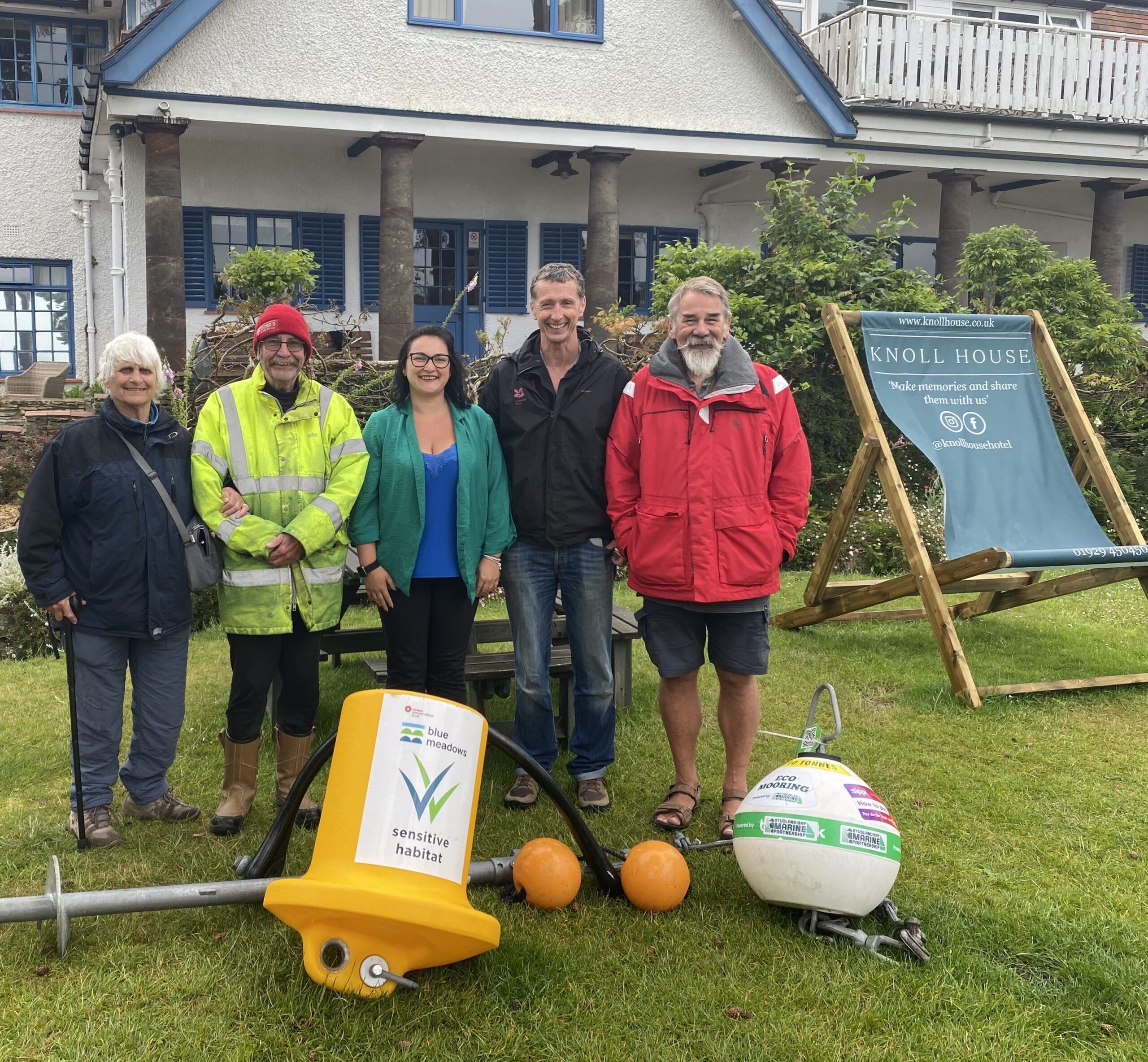 Five people standing outside the Knoll House Hotel with an eco-mooring laid out on the floor in front of them.