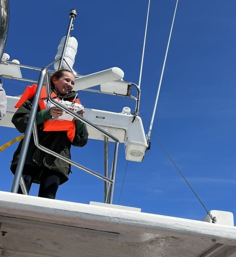 A woman standing on the side of a boat holding a remote control device.